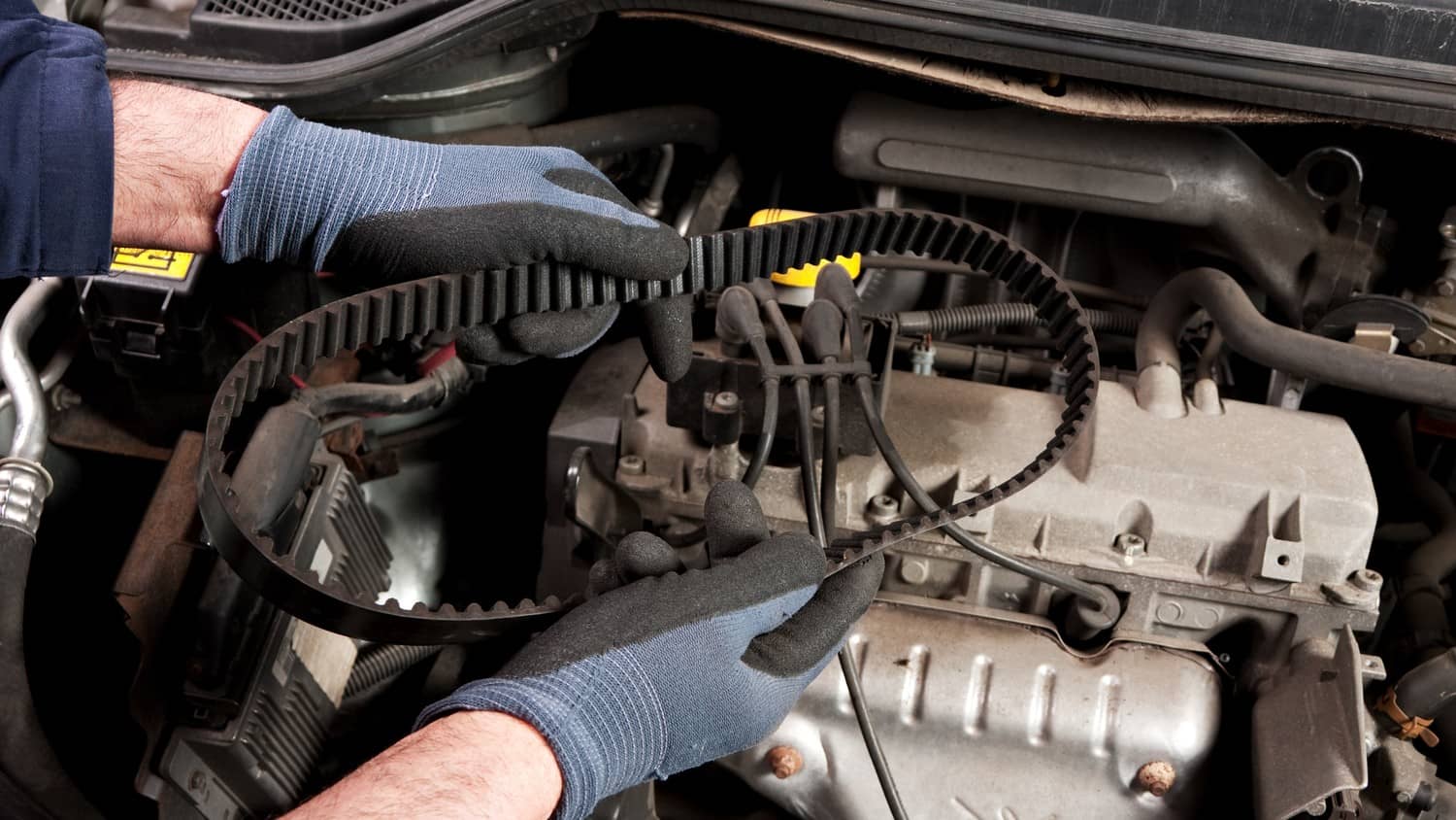 A mechanic working on a car engine, replacing the timing belt.