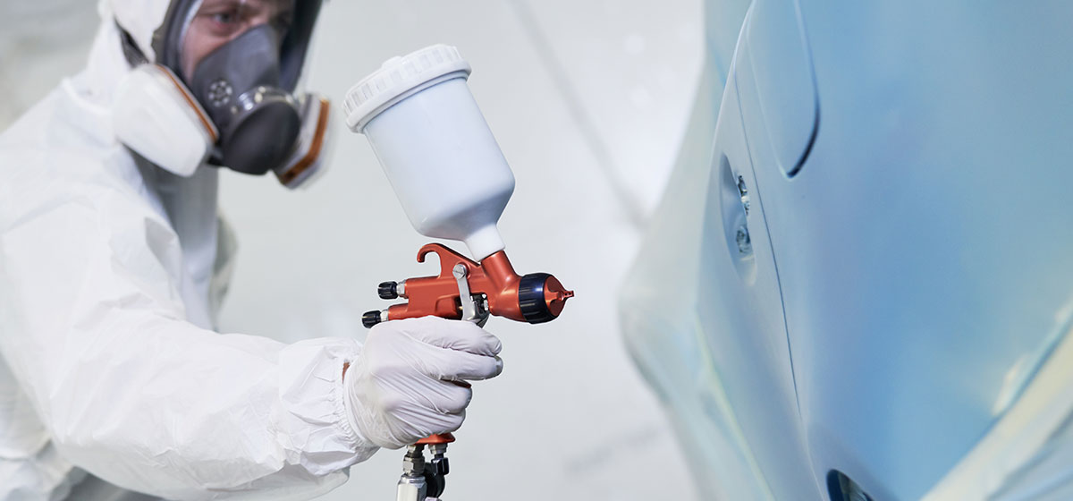 a car respray specialist spraying new paint on a car