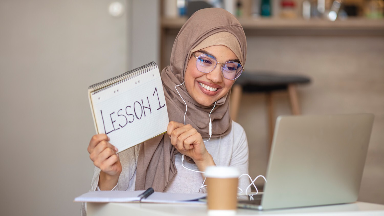 A person sitting at a desk, tutoring online. They are engaged in conversation and pointing at a notebook.