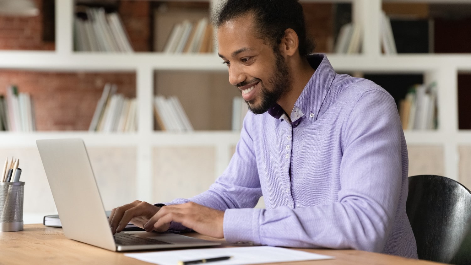 A person sitting at a desk, typing on a laptop.