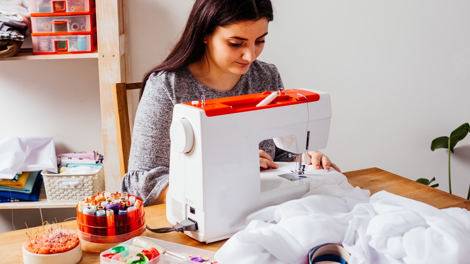 A close-up of a woman using a sewing machine stitching fabric, creating intricate alterations.