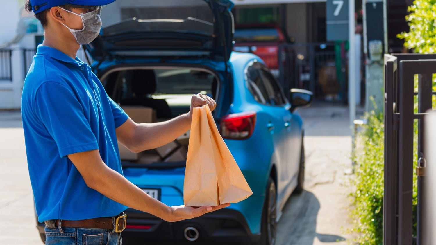 A close-up of a fast food delivery hero holding a bag of food, ready to deliver it to a customer.