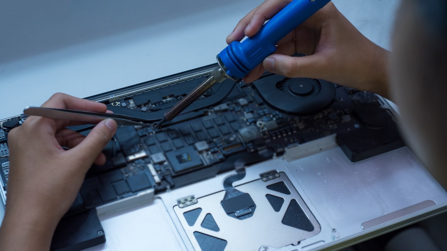 A close-up of a person repairing a laptop.