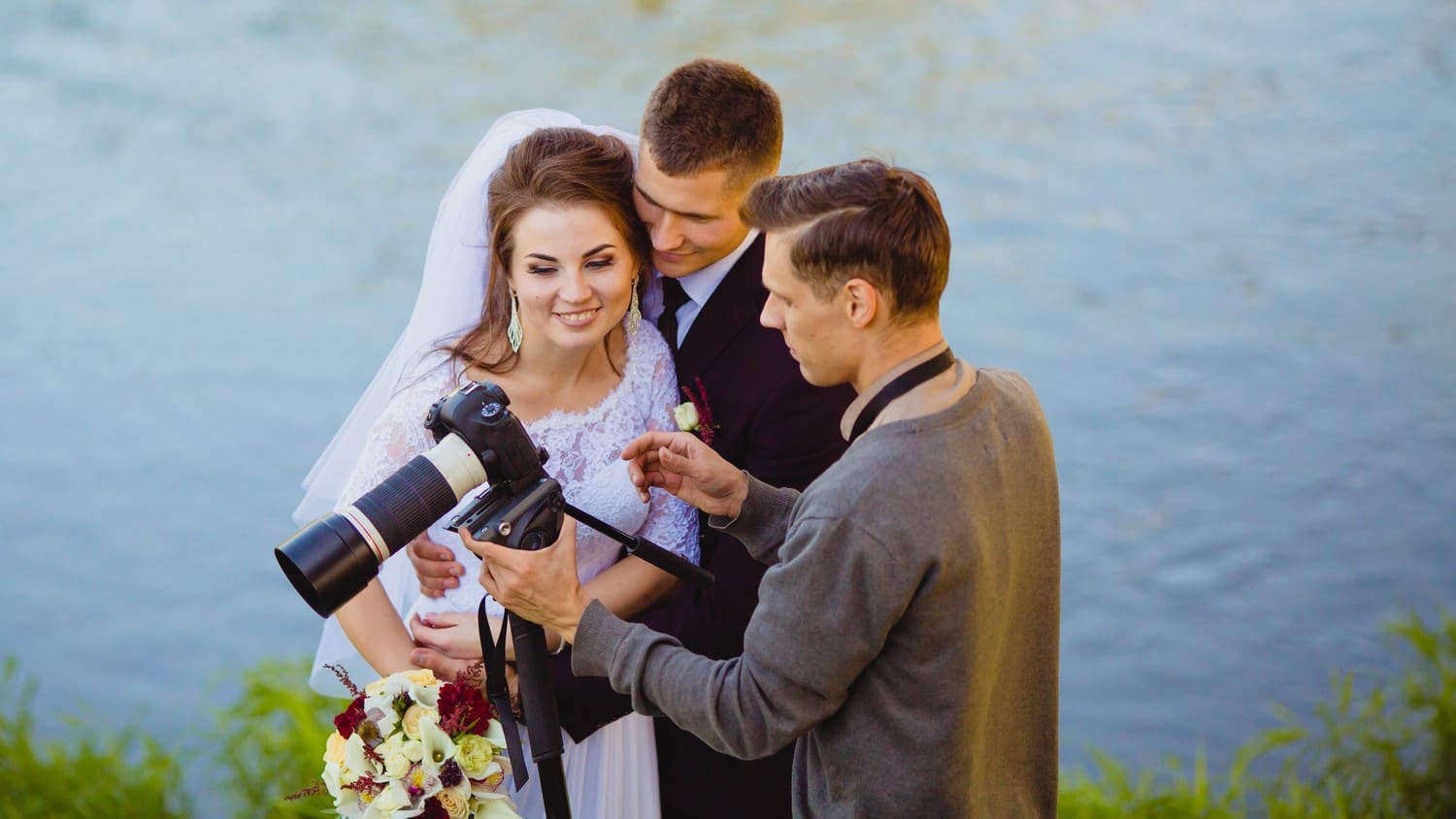 A beautiful bride and groom looking at a camera of their photographer