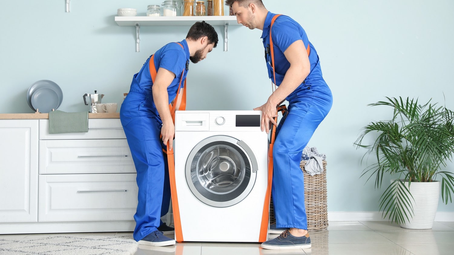 Two people on straps carrying a washing machine