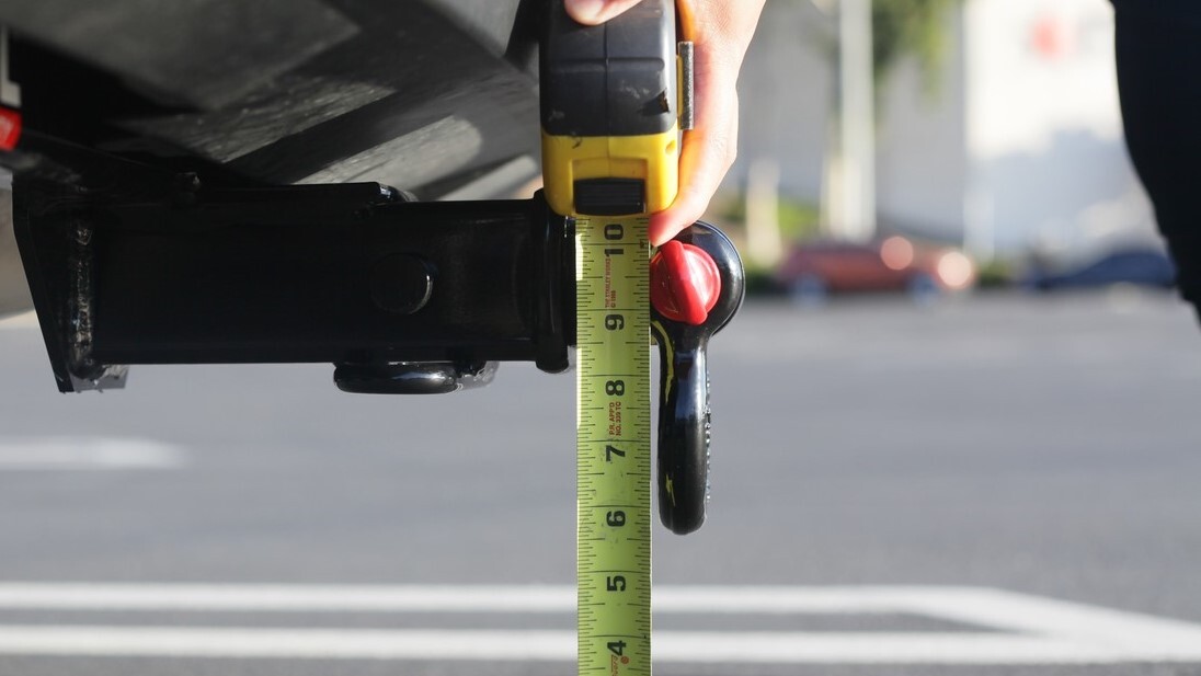 A professional installing a towbar on a vehicle, using tools and equipment, with a focus on precision and attention to detail.