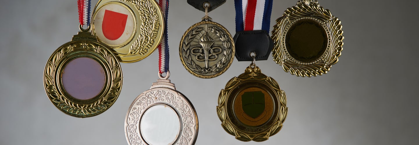 A close-up view of a hand holding a military medal, with colorful ribbons and intricate details, ready to be mounted.