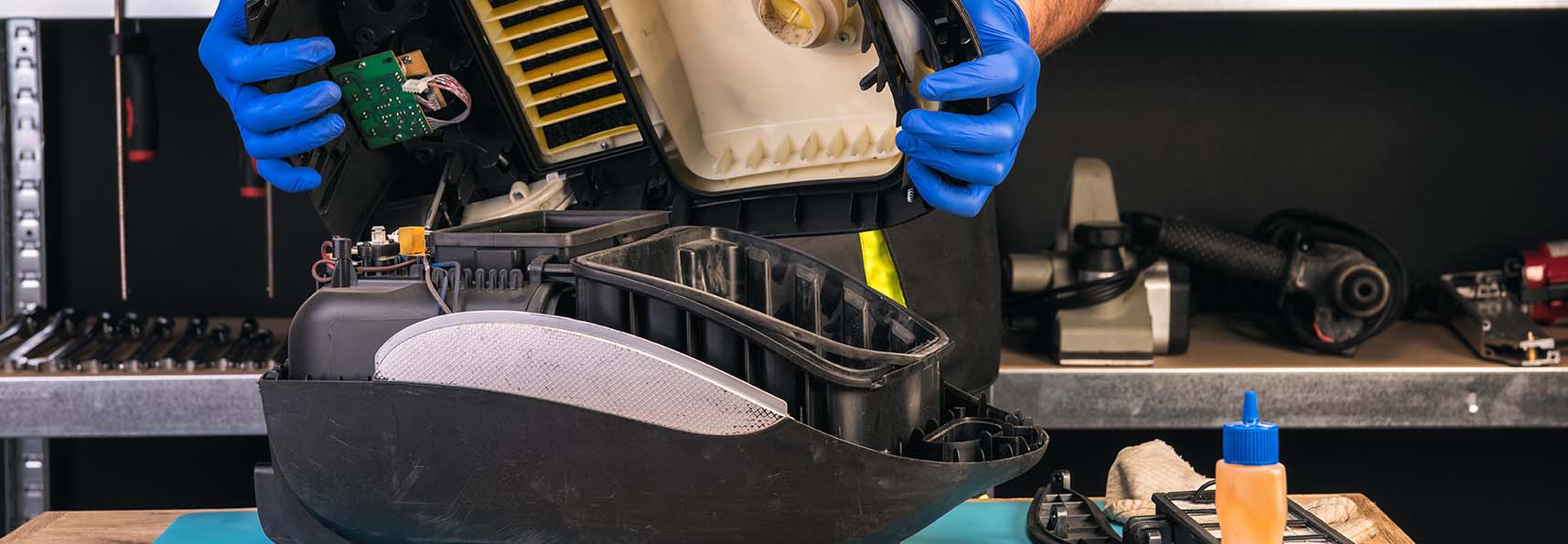 A person repairing a vacuum cleaner, focusing on the inner components and tools used for maintenance and fixing.