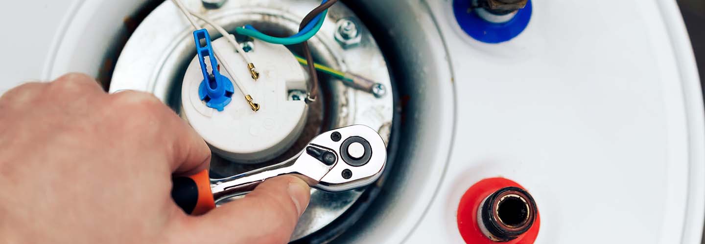 A man repairing a water heater with tools and equipment