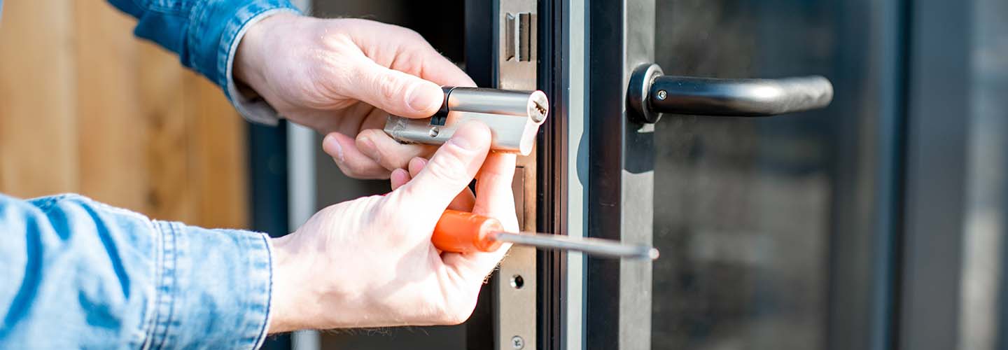 A close up photo of a  mobile locksmith holding a lock he is about to install on a door.
