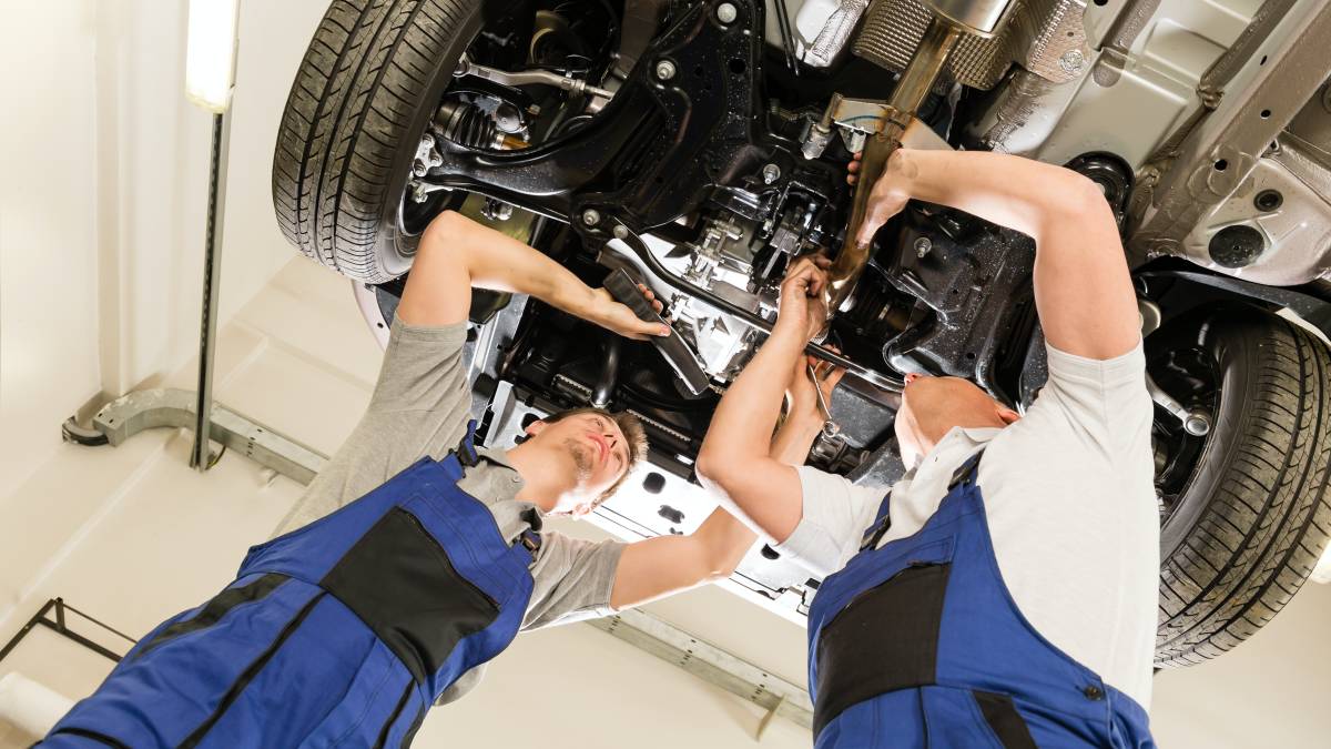 auto mechanic checking car under chasis