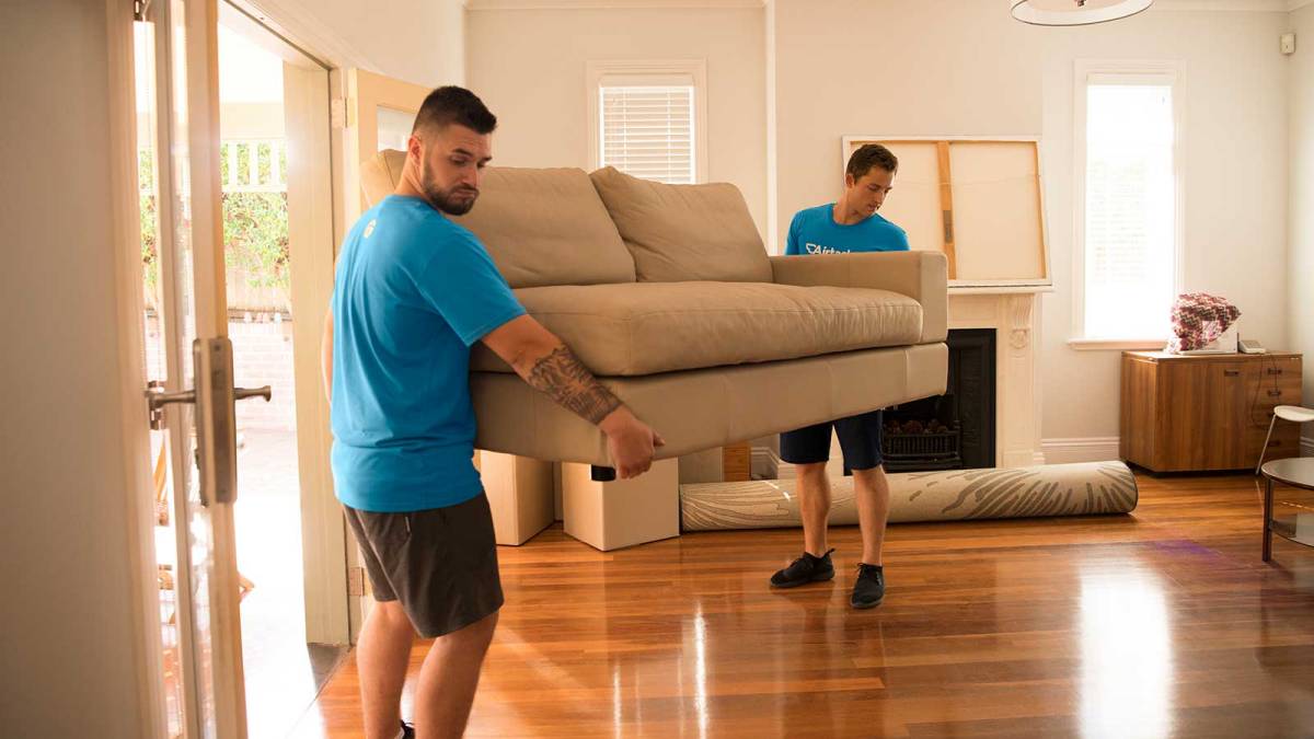 Removal service professionals moving a couch inside the house