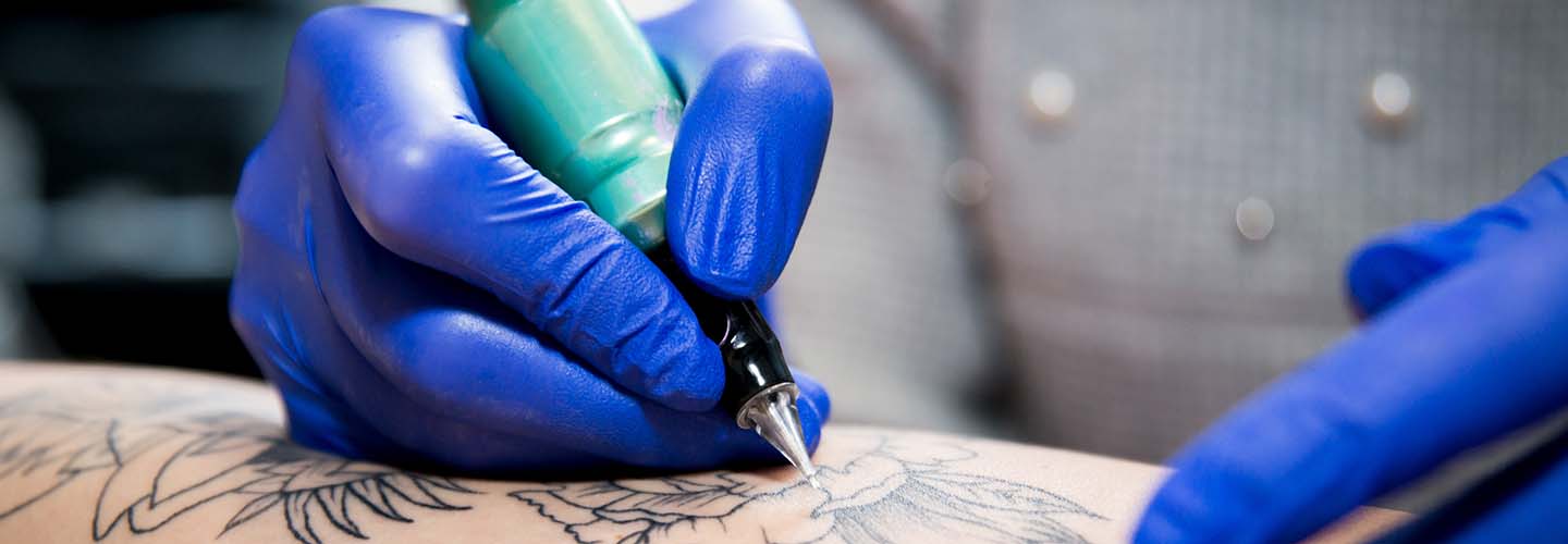 A skilled tattoo artist working on a client's arm, carefully creating intricate designs with a buzzing tattoo machine.