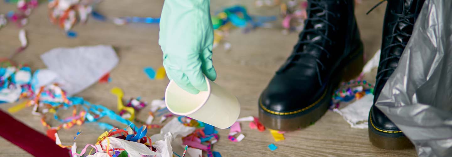 A person cleaning up after a party, picking up trash to tidy the place.