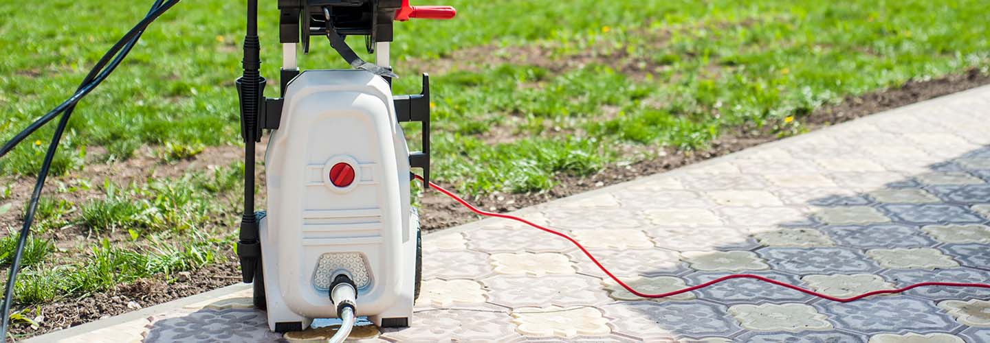 A close-up of a pressure washer set on a walkway next to the yard.