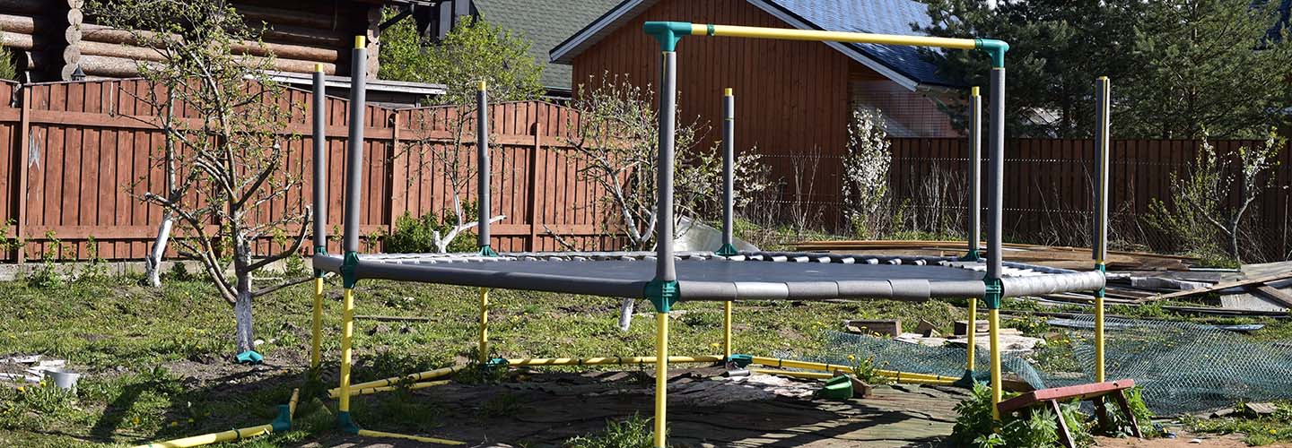 A trampoline in a backyard in the middle of assembly.