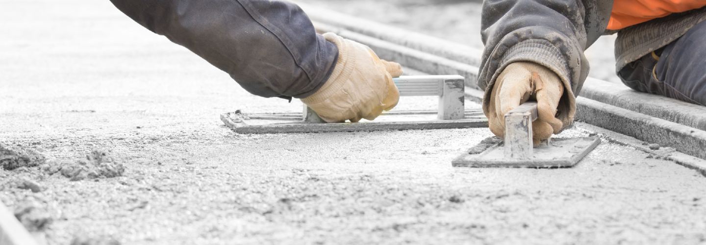 A close-up photo of a person repairing a paved pathway, using a trowel to fill in gaps with fresh mortar.