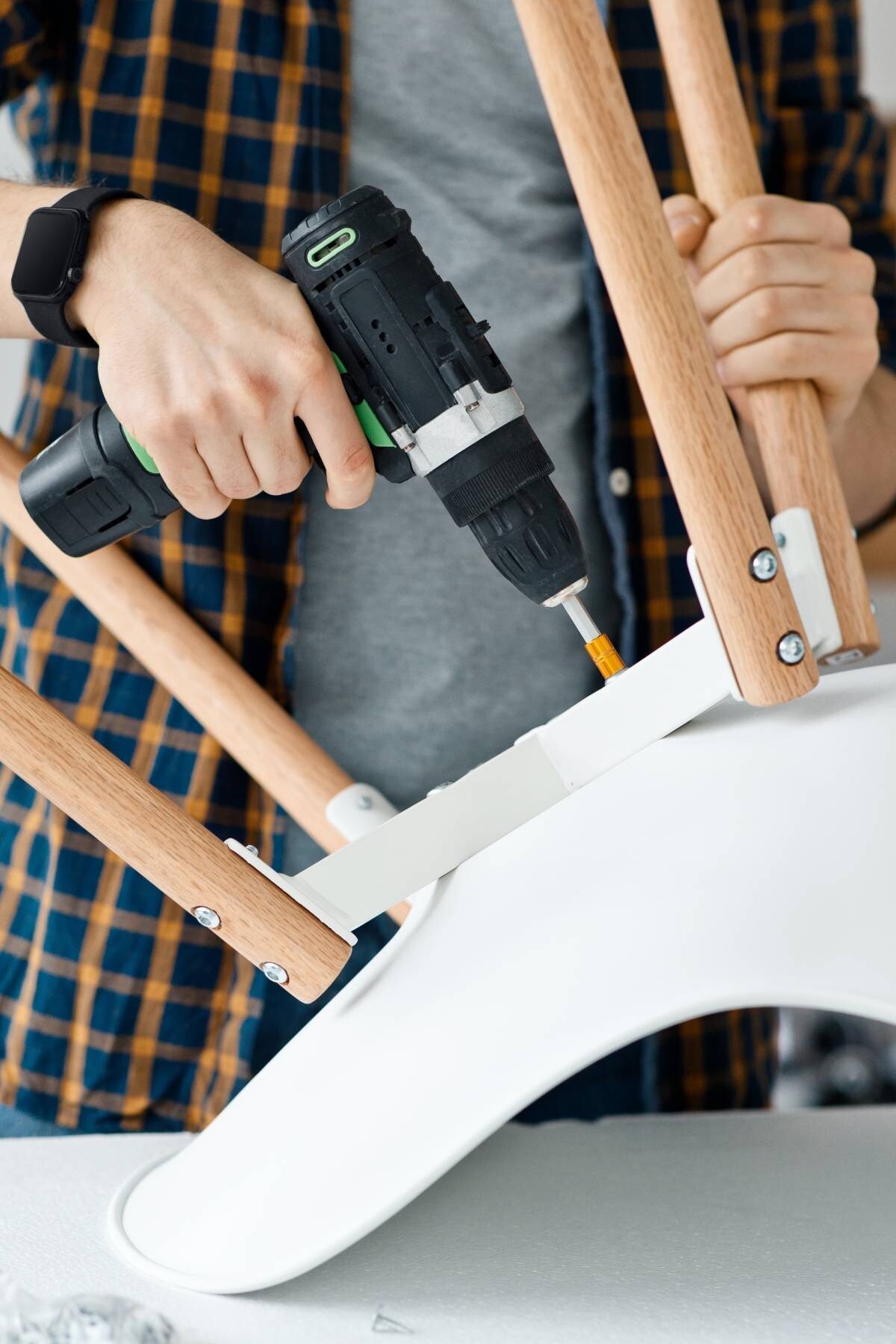 a man drilling screws on a white chair