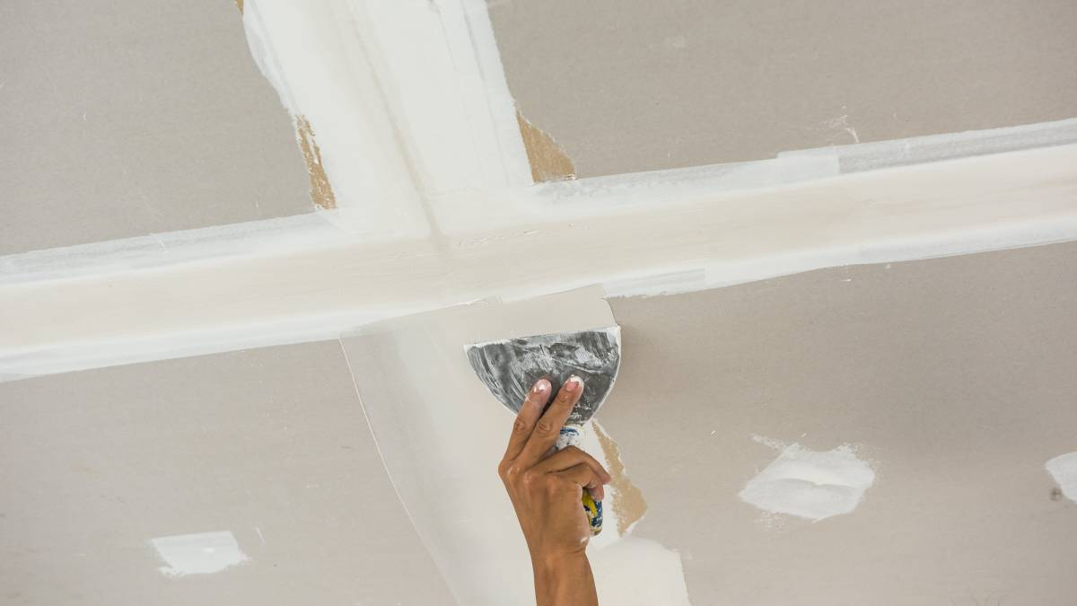 Hand using tool to plaster ceiling