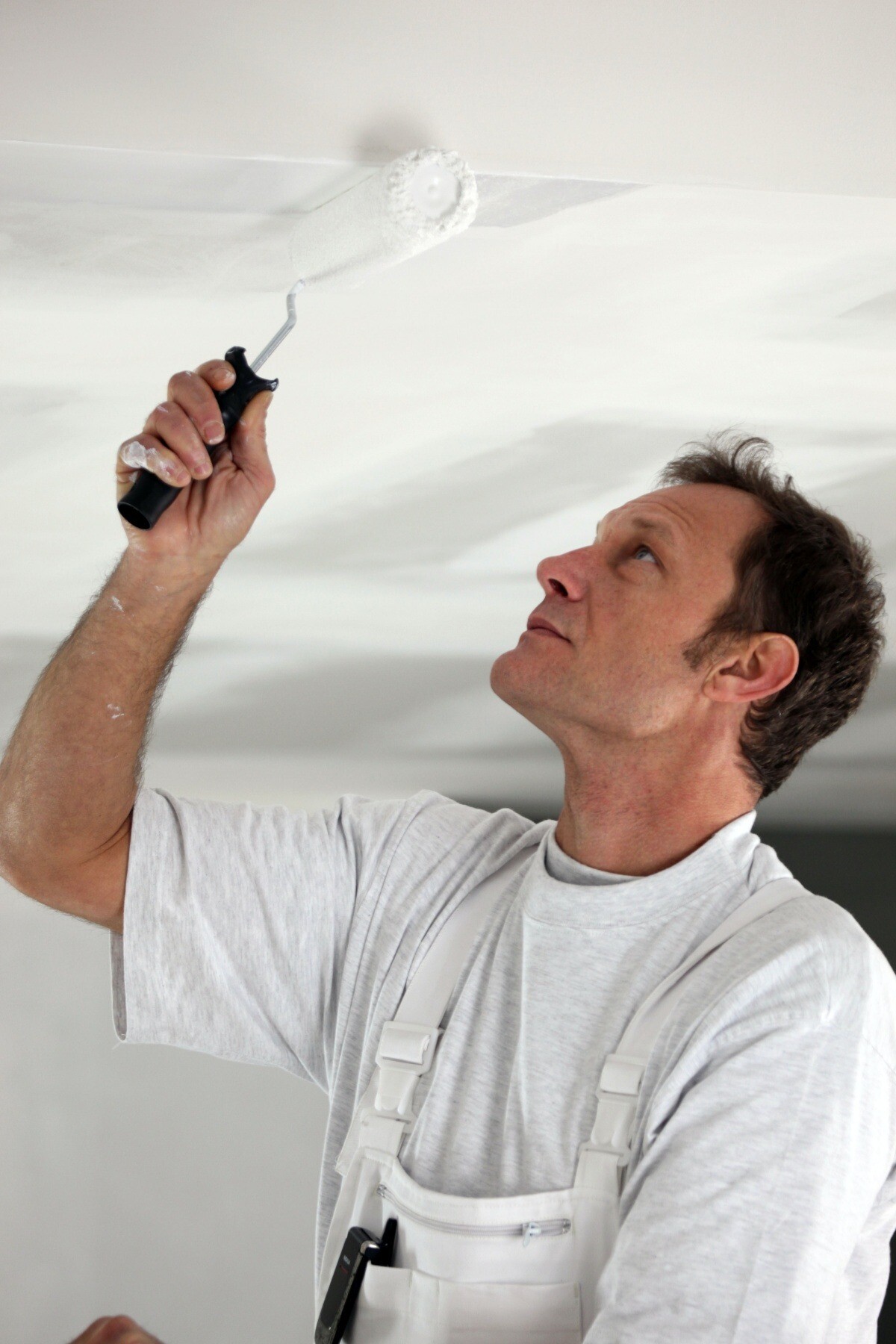 man painting ceiling white