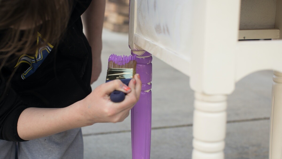 a woman painting a piece of furniture