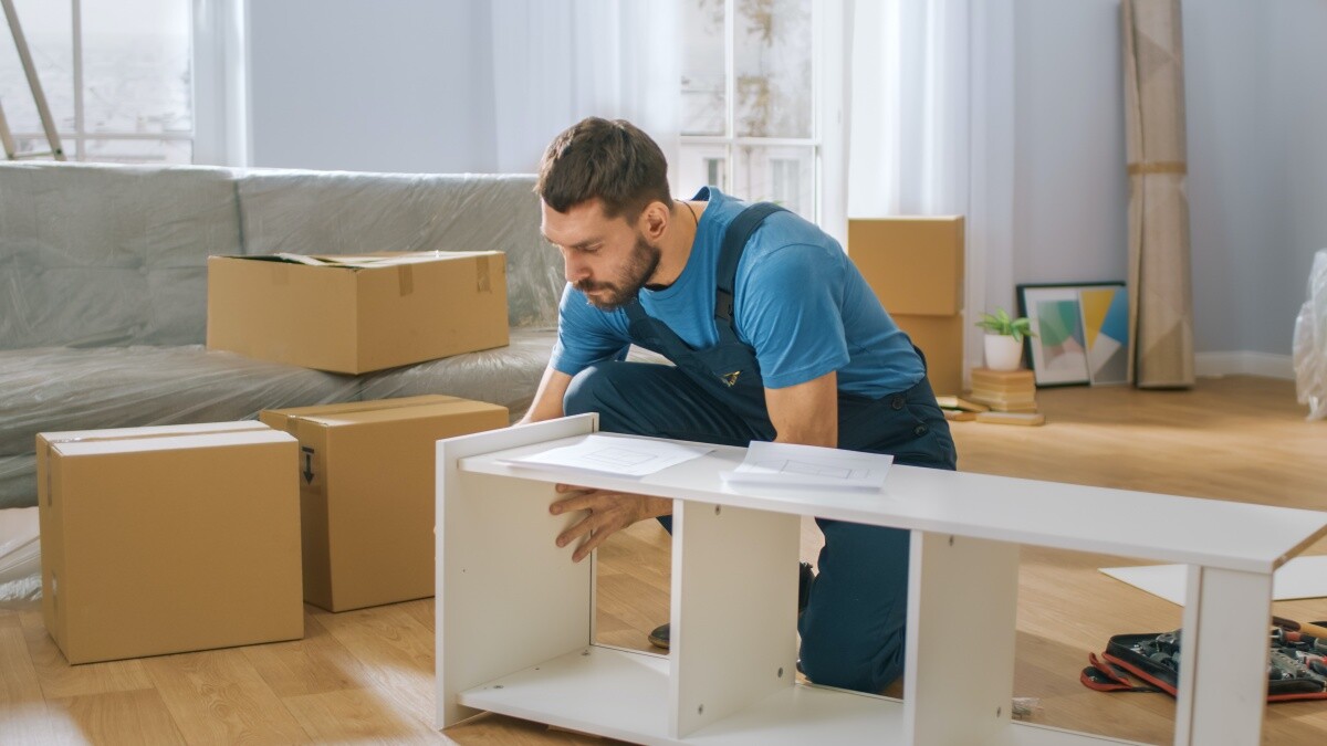 man wearing blue shirt assembling white bookcase