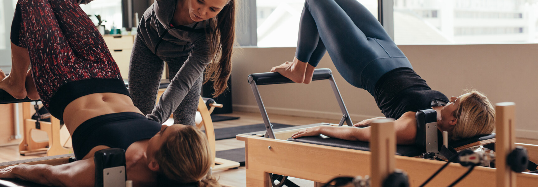 A Pilates instructor leading a class, guiding participants as they perform the excercises.