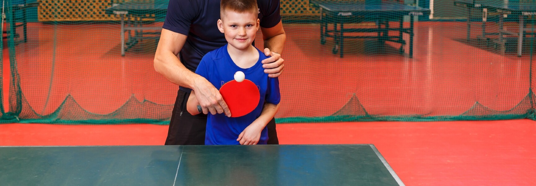 A kid being taught how to play table tennis.