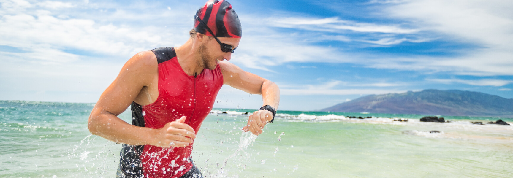 A triathlete running along a scenic coast with the ocean in the background and a clear blue sky above.