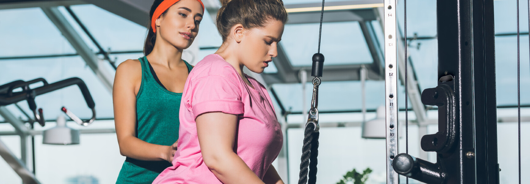 A woman using a cable machine in a gym, focused and determined