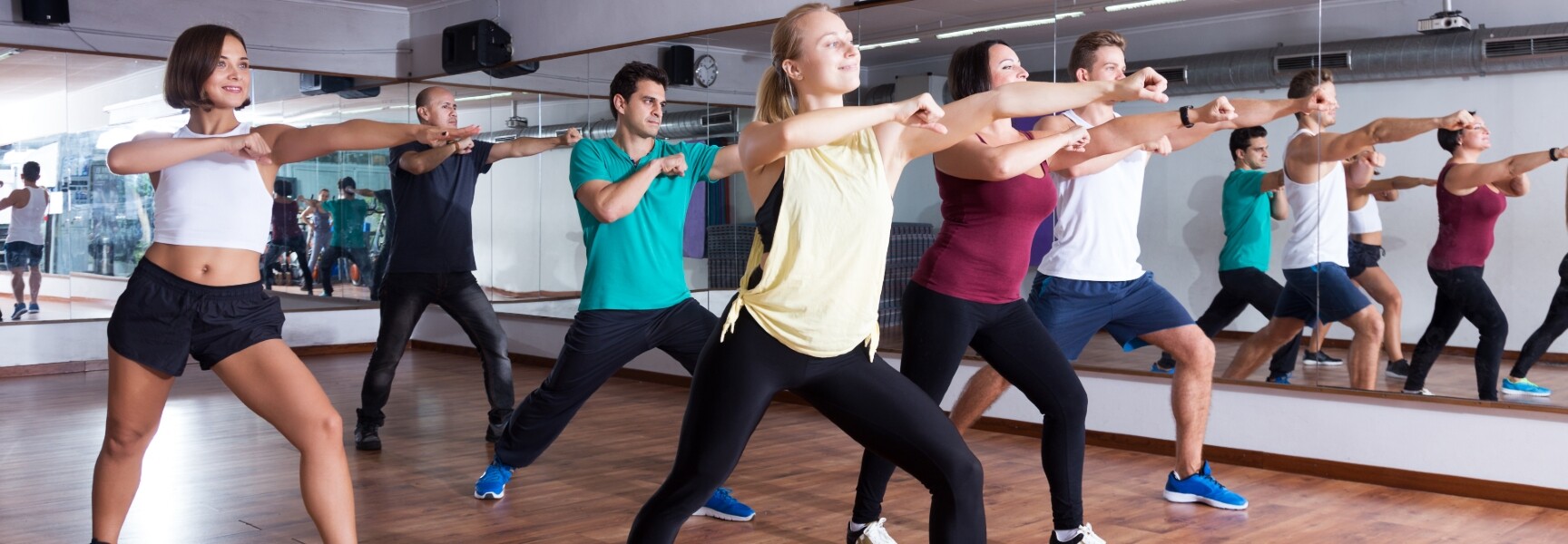 A group of people dancing energetically in a Zumba class, with bright lights creating a lively atmosphere.