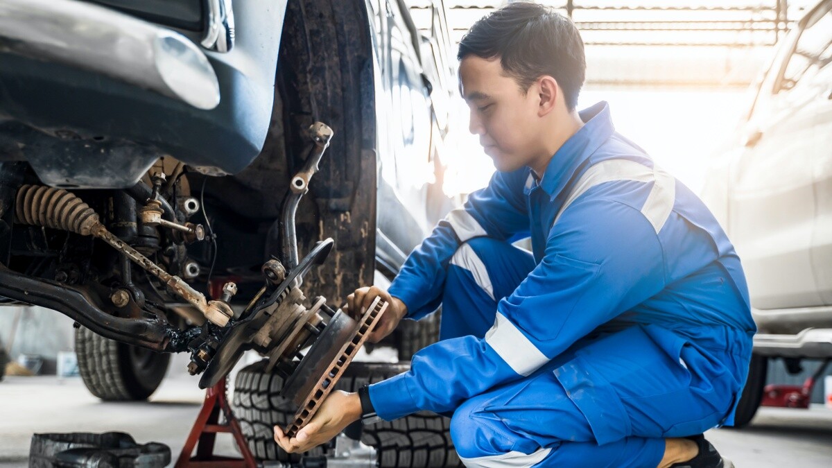 mechanic wearing blue fixing car tire