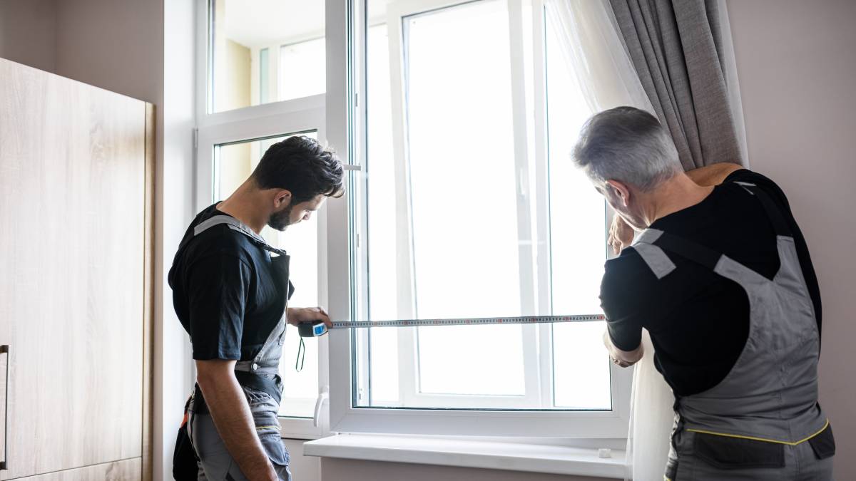 two men measuring a window for blinds installation