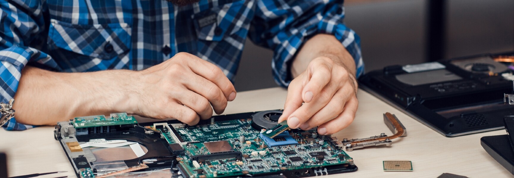 A person repairing a laptop with the circuit board exposed.