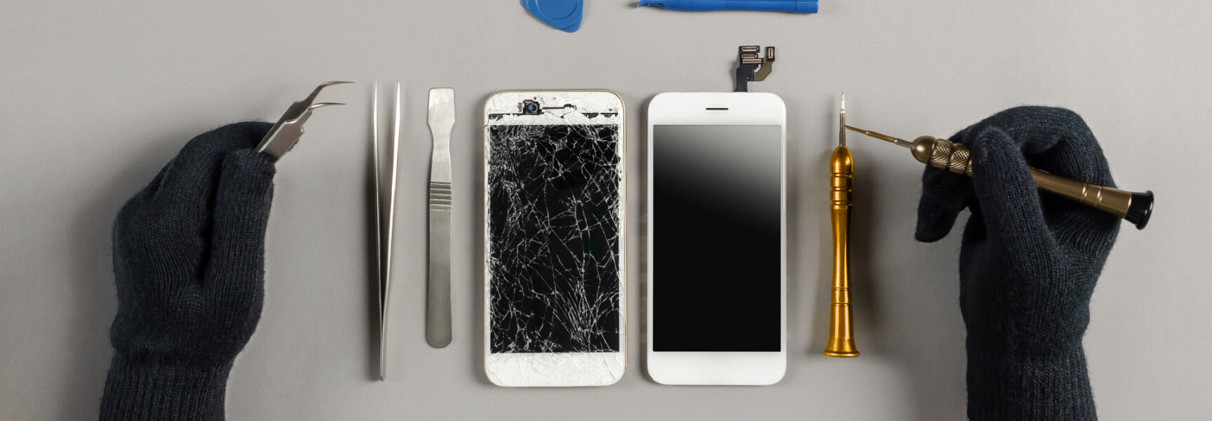 A person repairing a cracked smartphone screen with a toolkit, showing precision and expertise in fixing electronic devices.