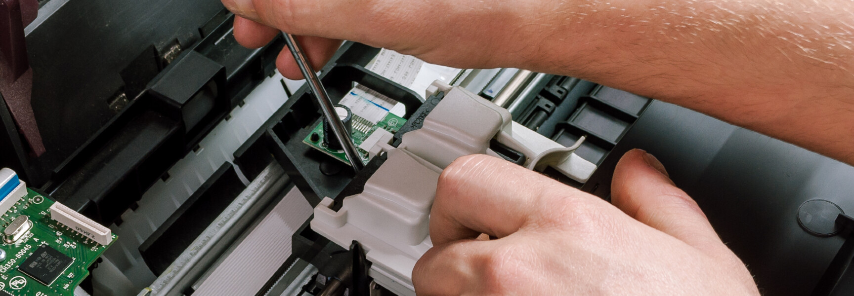 A close-up image of a printer being repaired.