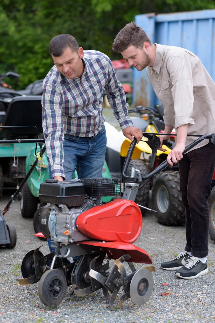two men repairing a lawnmower