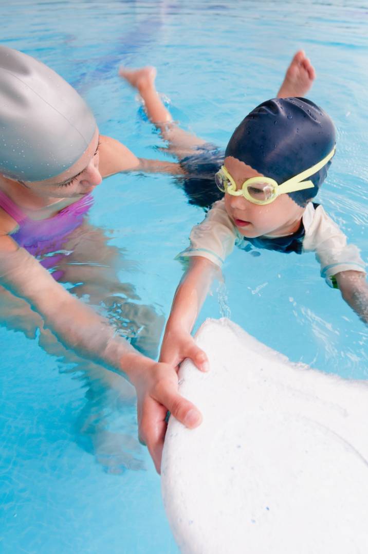 a woman teaching a little boy how to swim