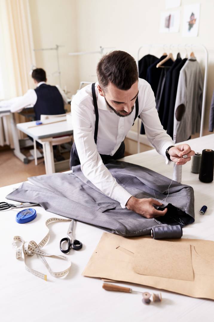 a man sewing a blazer in a workshop