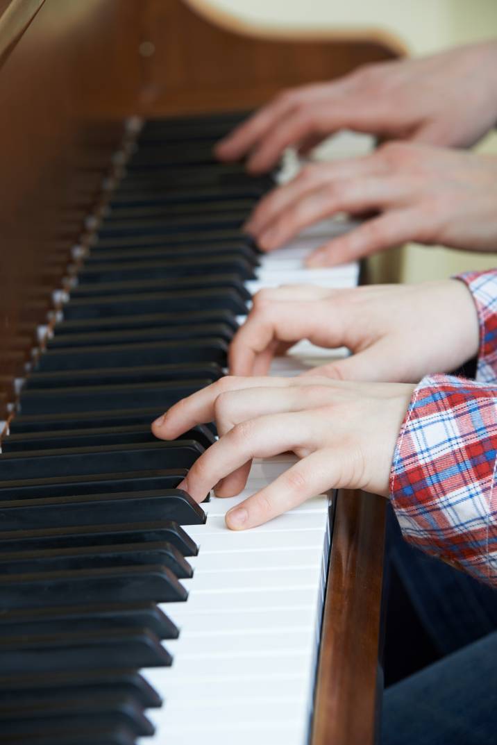 a teacher and their student playing a piano duet