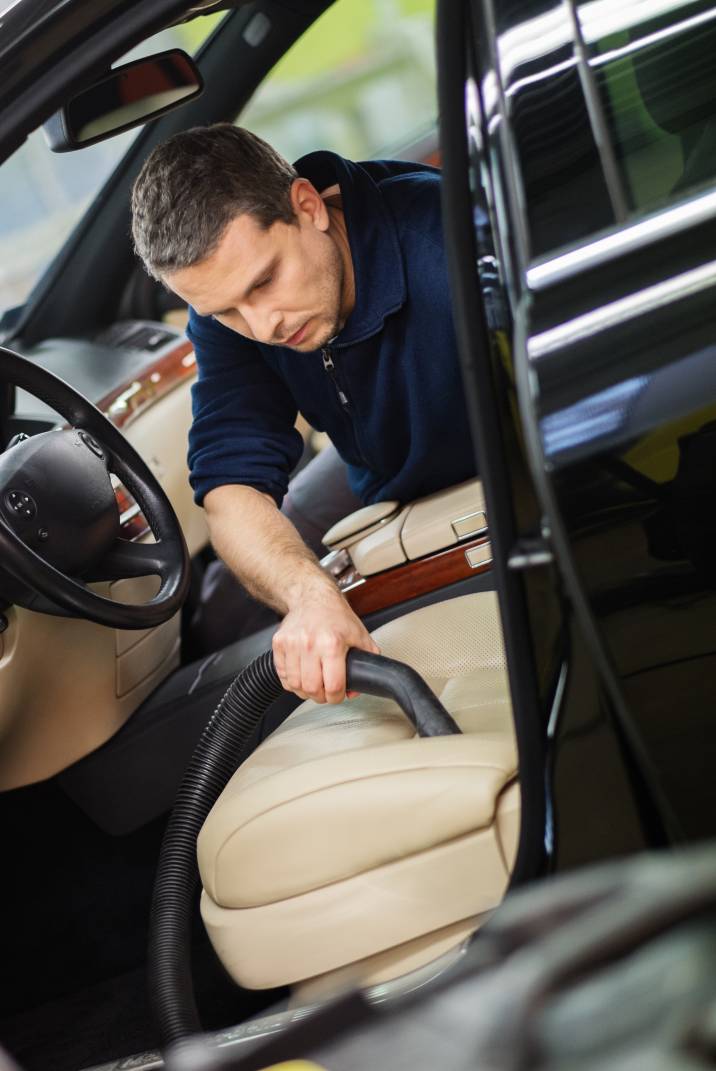 a man vacuuming a car seat