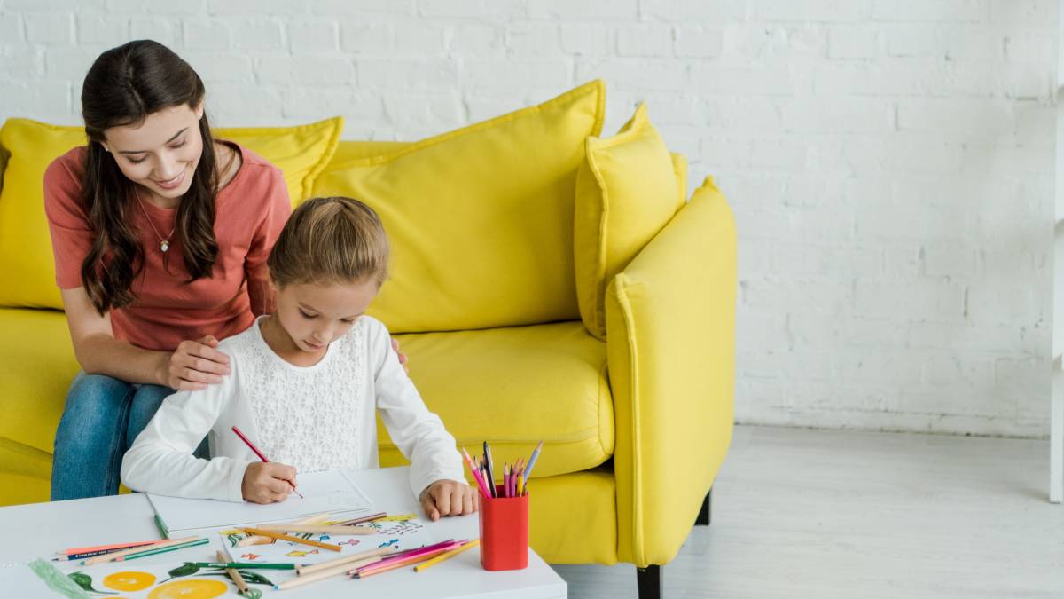 nanny watching a little girl draw