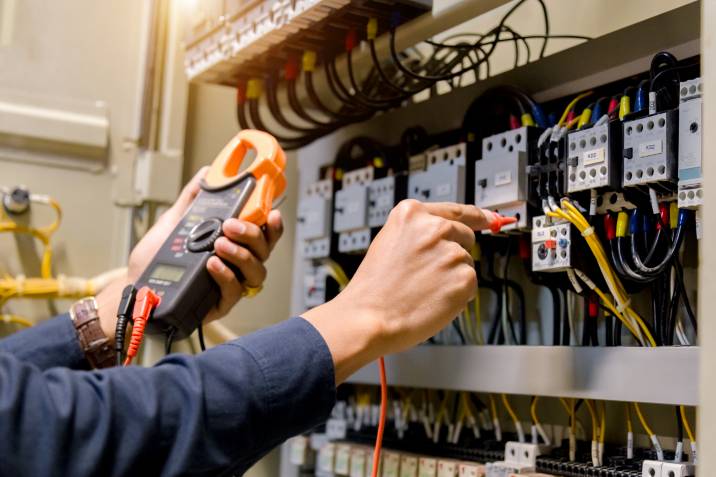 electrician using voltage metre to check voltage and power of outlet