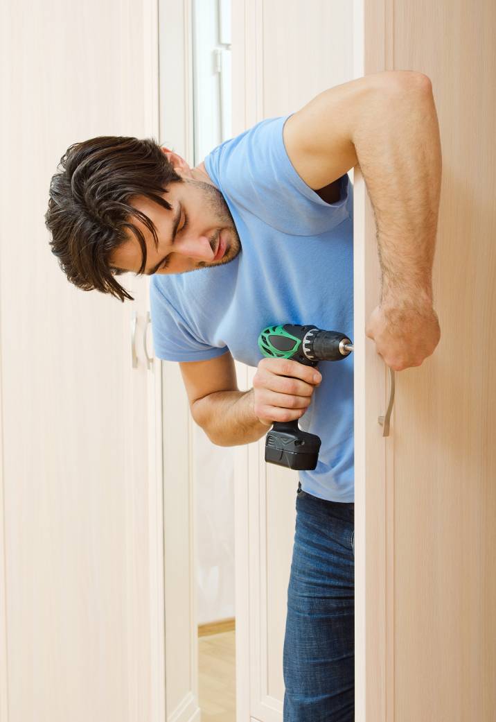 a bearded man drilling a hole in a door