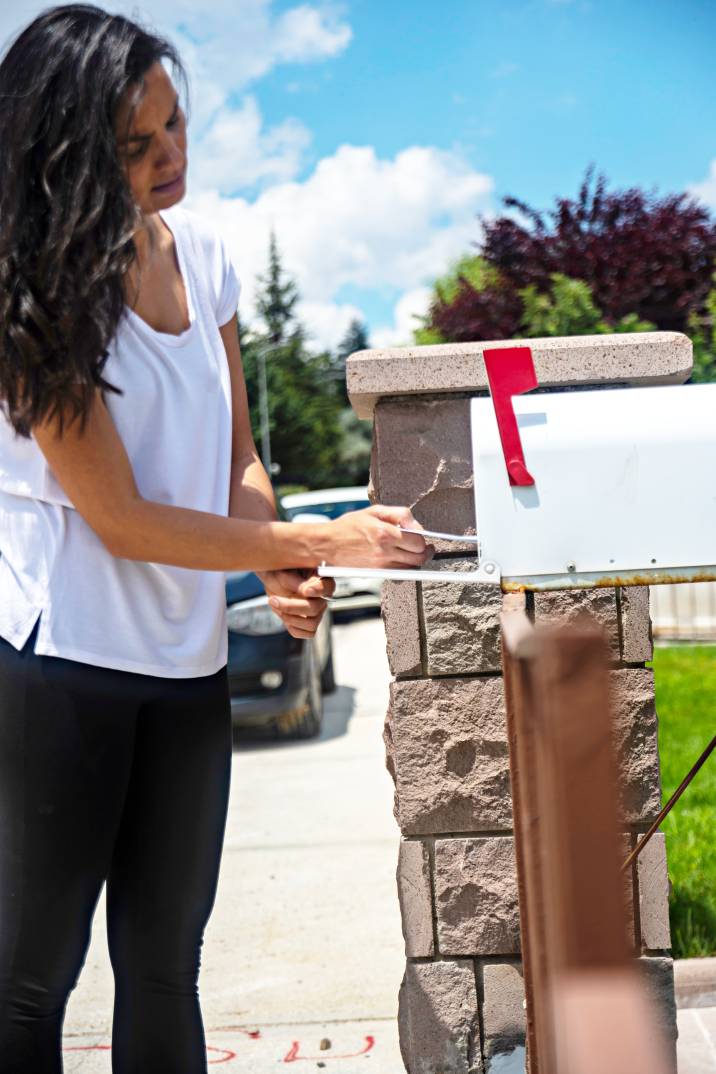 a woman getting a letter from a mailbox