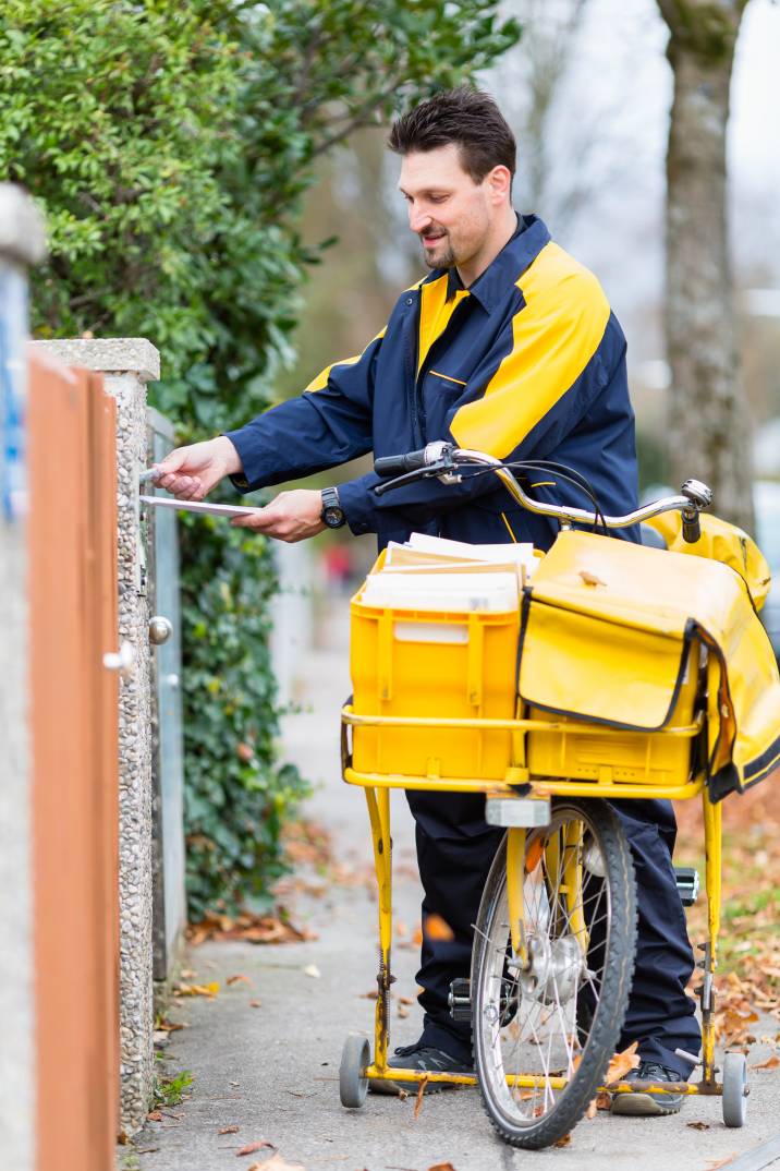 a postman putting a letter in a residential mailbox