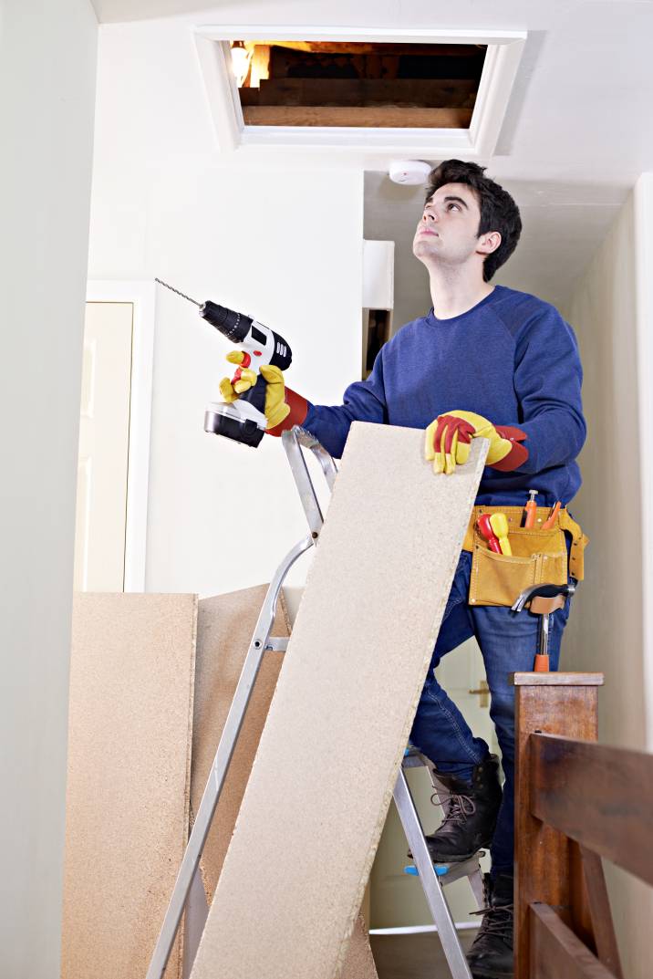 a handyman examining the entrance to an attic