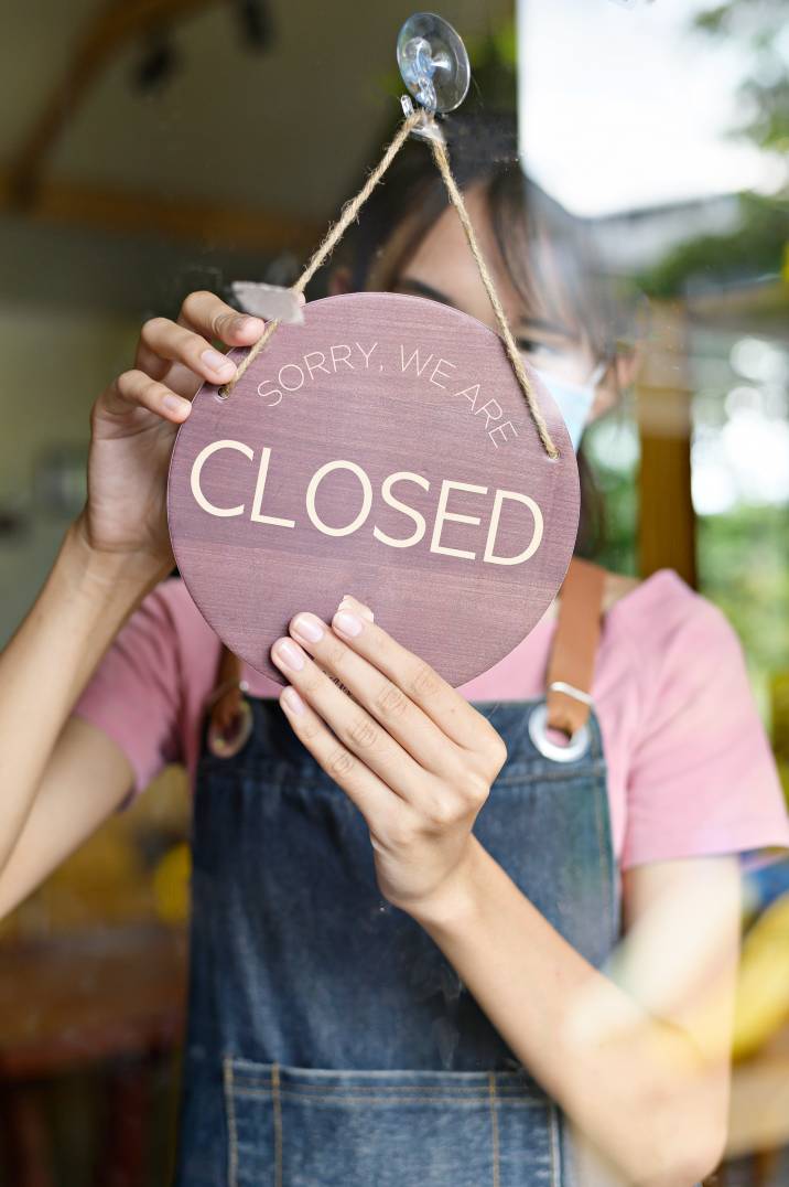 a cafe employee turning a sign for closing time