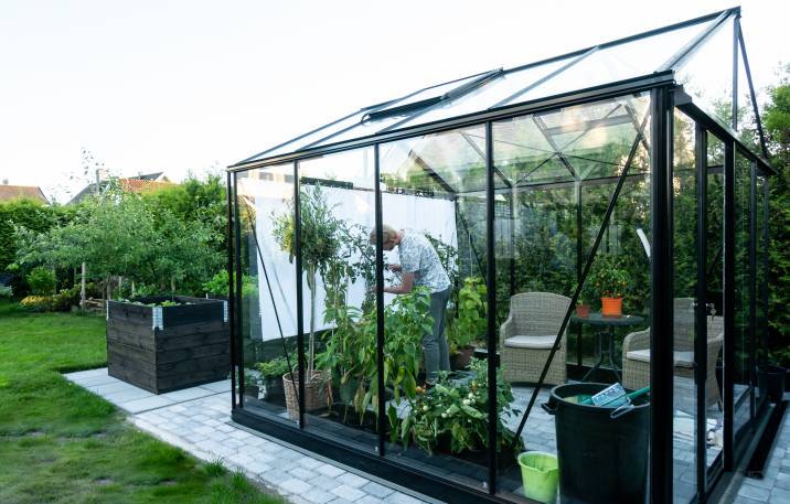 man holding a plant pot inside a greenhouse