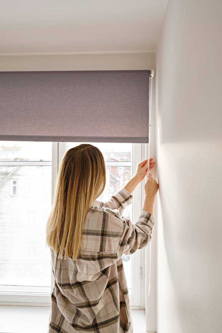 a woman adjusting window blinds